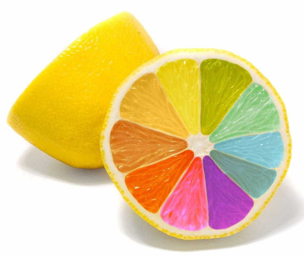 Cut lemon showing rainbow colored segments inside.